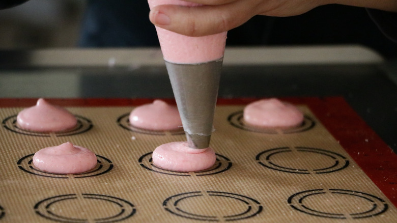 Piping macaron batter onto a macaron mat