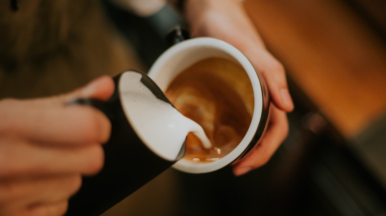 barista pouring milk into espresso