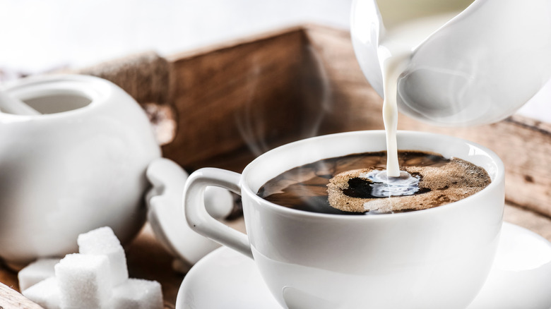 pouring milk into coffee cup