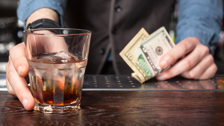 Bartender serving drink and holding tips
