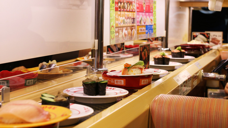 A conveyor belt full of sushi plates inside restaurant