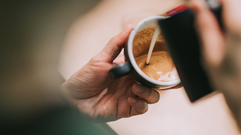 barista adding milk foam to latte