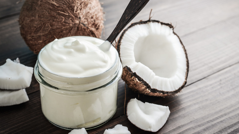 A jar of coconut cream next to a coconut