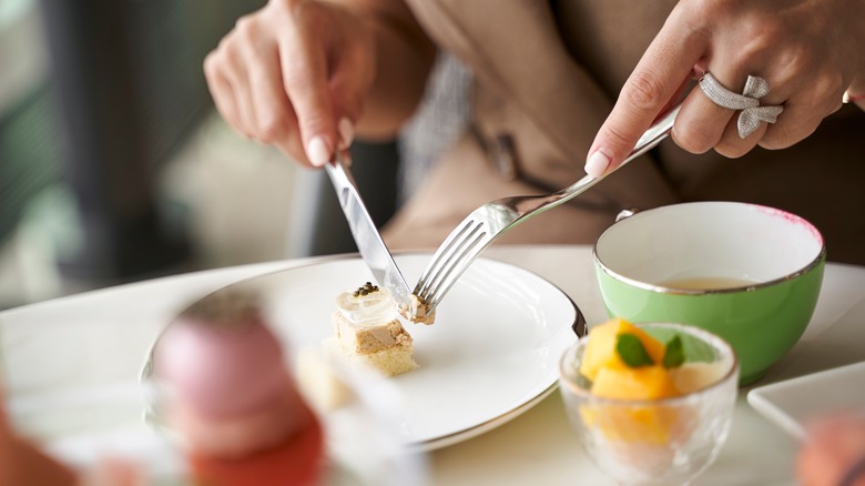 Woman cutting dessert with fork and knife