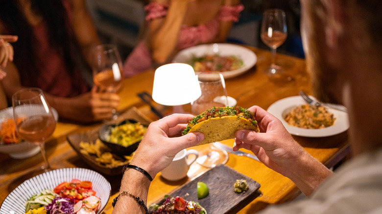 Man eating taco with wine