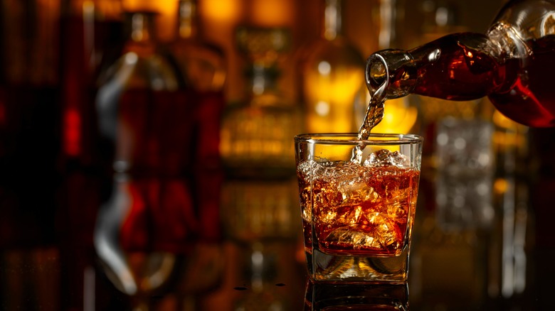 Pouring whiskey into a glass with ice