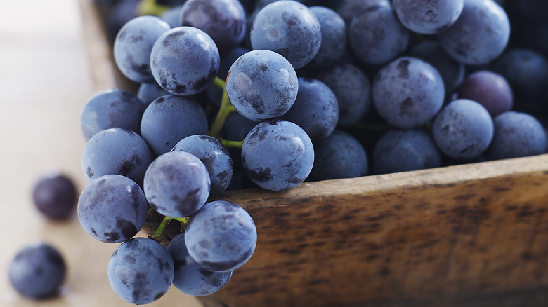 bunch of purple grapes in wooden bowl