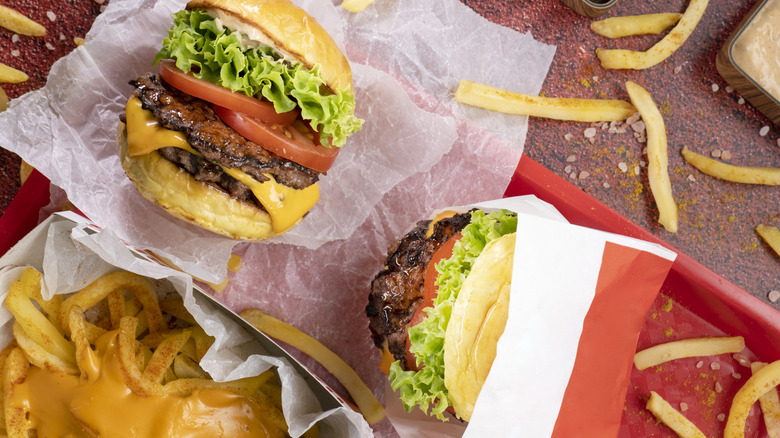 Fast food burgers sit on a tray with fries.