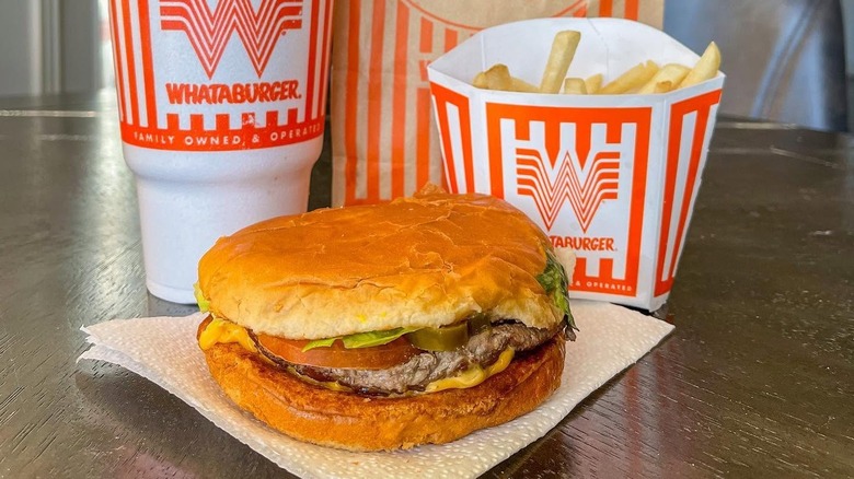 A Whataburger sits in front of branded fries and a drink.
