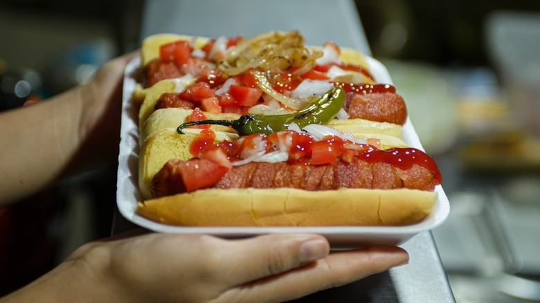 Hands holding tray of hot dogs