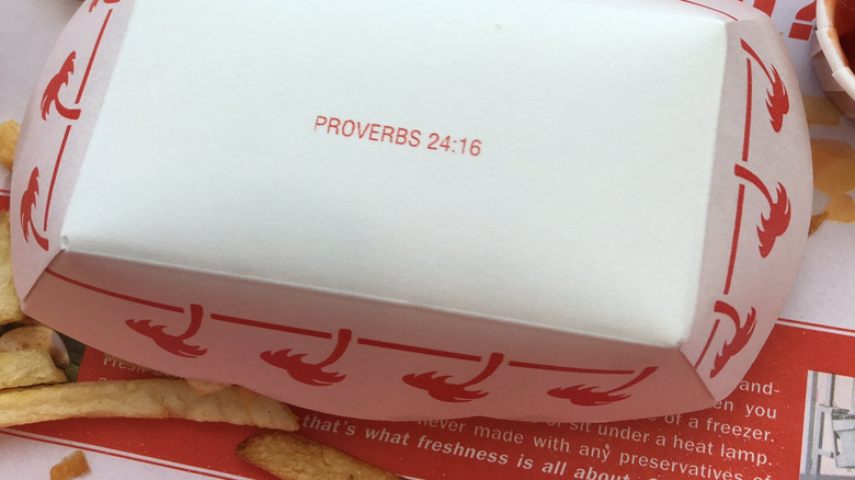 The Bible verse Proverbs 24:16 is displayed on the bottom of an In-N-Out Burger french fry container