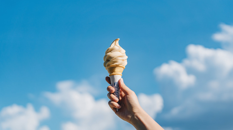 Hand holding ice cream or custard cone up to the sky