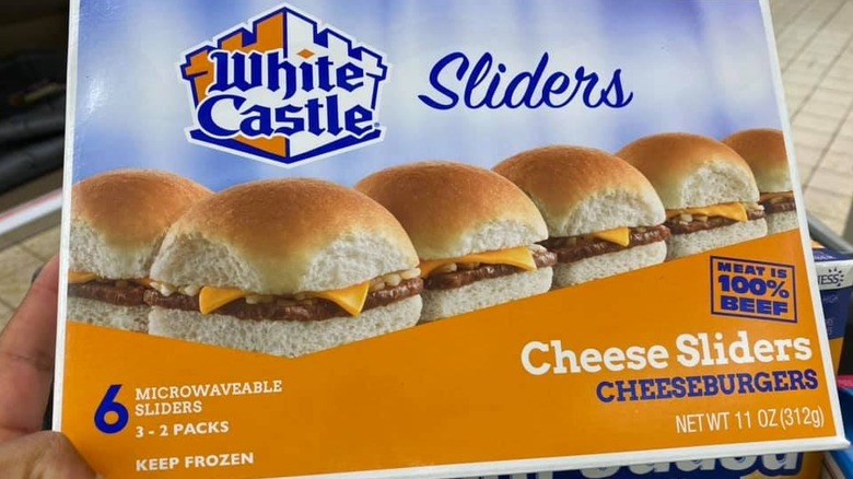 A hand holds out a box of White Castle microwaveable sliders