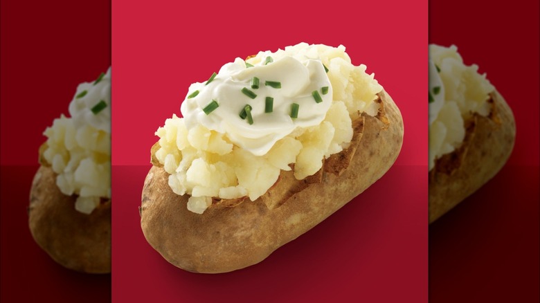A Wendy's baked potato with sour cream and chives against a red background