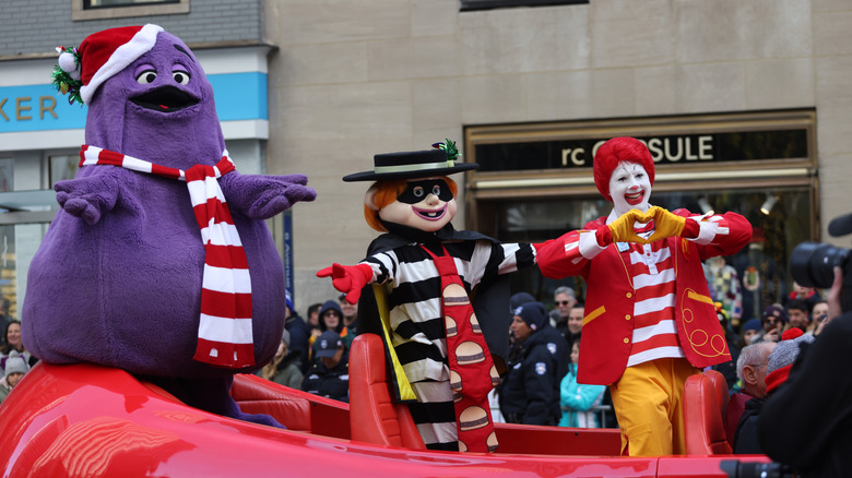 Grimace, the Hamburglar, and Ronald McDonald ride in a red car during the Macy's Thanksgiving Day parade