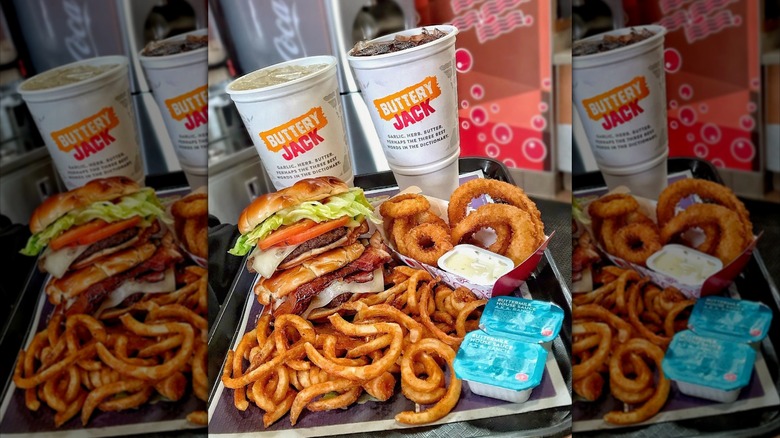 A Jack in the Box soda, burger, fries, and takeout bag sit on a wooden surface