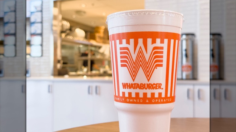 A Whataburger soda cup is pictured, with the restaurant in the background