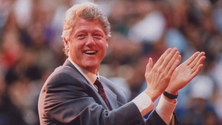 U.S. President Bill Clinton claps in front of a crowd outdoors