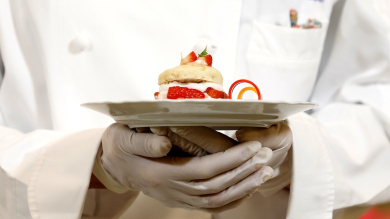 White house chef holds plate of strawberry dessert