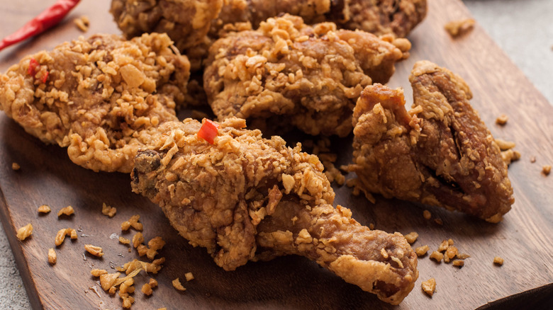 Spicy, crunchy fried chicken on a wooden slab
