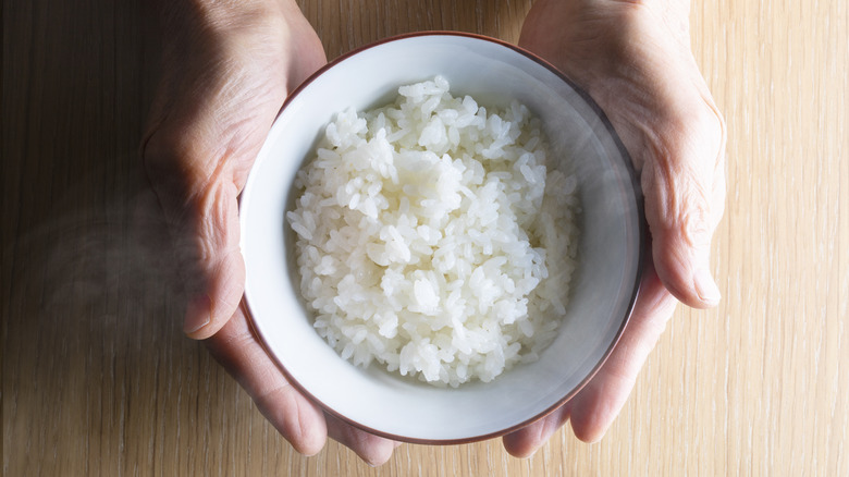 Hands holding bowl of white rice