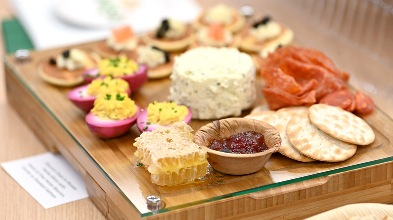 Boursin on a charcuterie board with deviled eggs, crackers, honey, and jam
