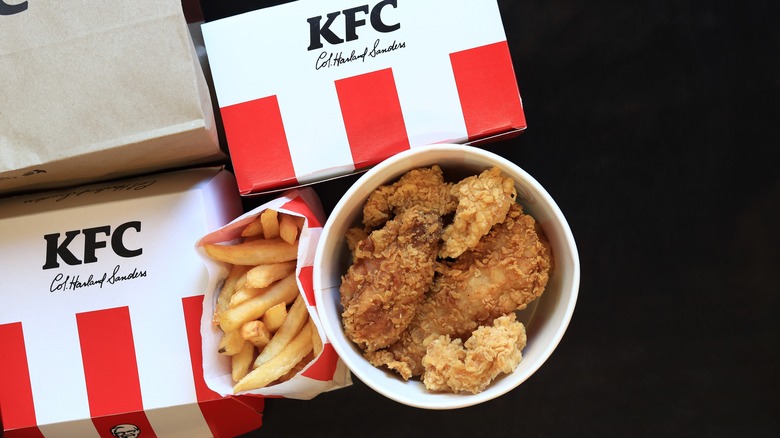 Kentucky Fried Chicken (KFC) bucket of fried chicken and fries next to boxes of menu items with KFC branding