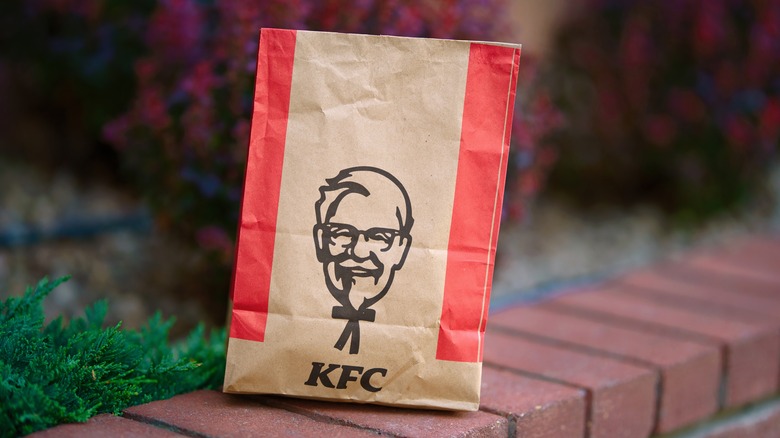 A brown and red KFC takeout bag with a printed photo of colonel sanders