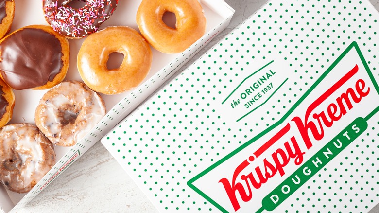 An open box of Krispy Kreme donuts and the box's lid sit adjacent to each other
