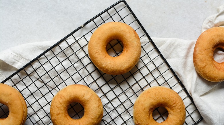 Freshly cooked donuts sit on a cooling rack