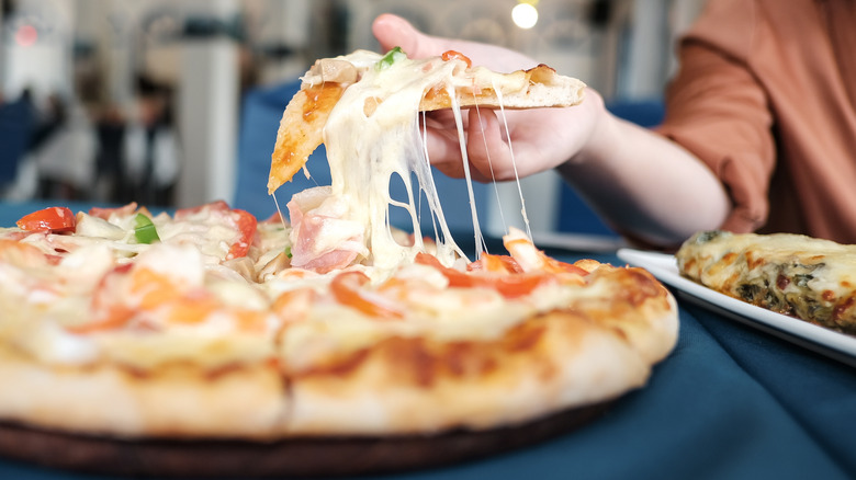 person picking up pizza slice