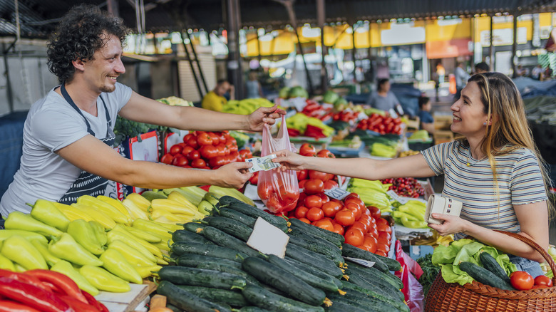 woman paying for vegetables with cash