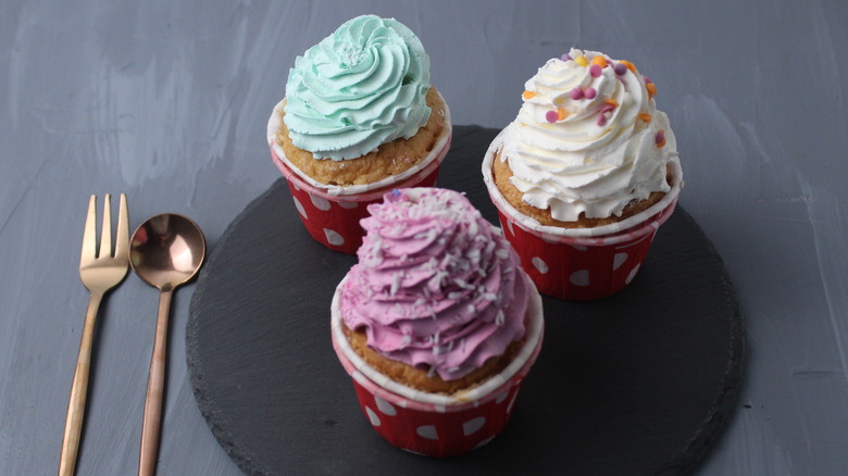 three cupcakes on a board
