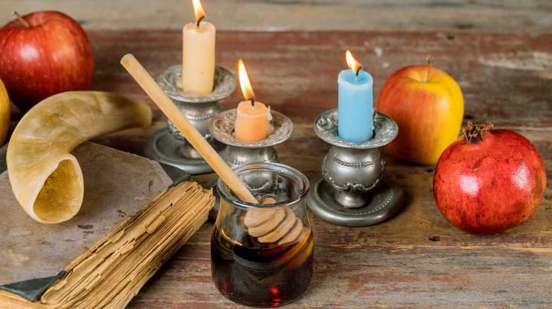 Shofar with apples, pomegranate, honey, old book, and candles