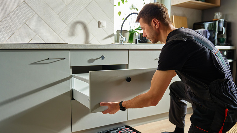 A person assembling a kitchen drawer.