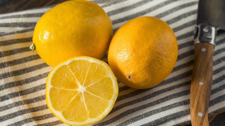 Whole and halved lemons on striped towel