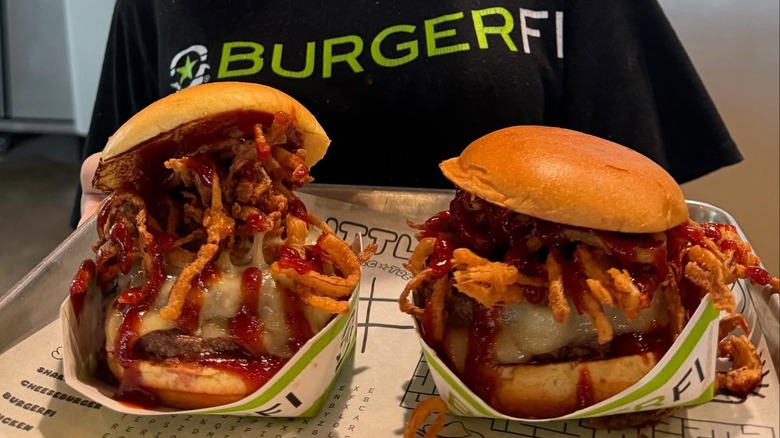 Two incredibly large burgers from the chain BurgerFi sit on a tray