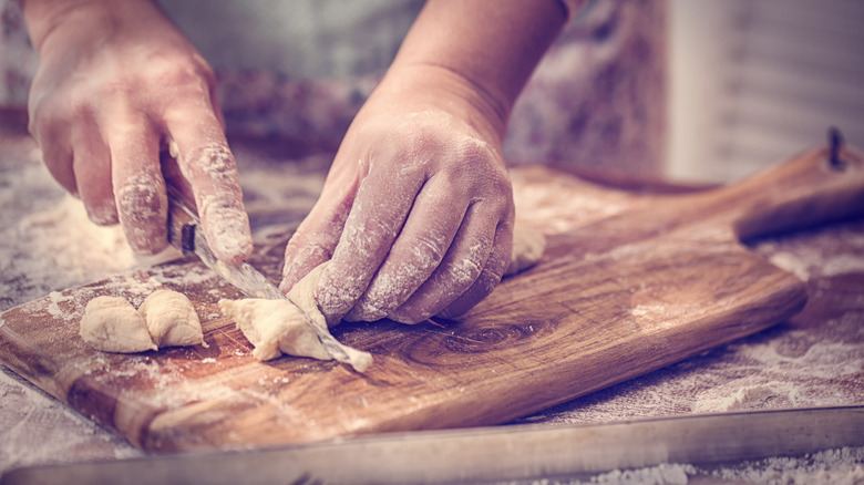 A pasta chef cuts gnocchi into two separate pieces