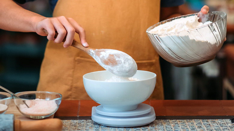Hands measuring flour onto scale