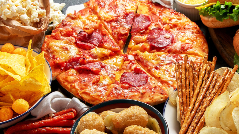 Pizza surrounded by various snacks
