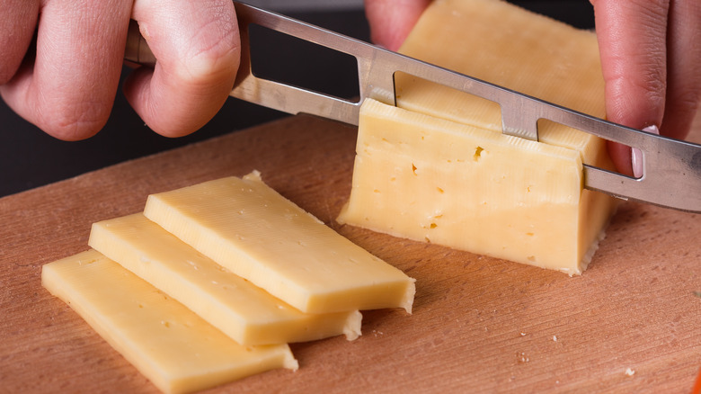 slicing cheese with knife on board
