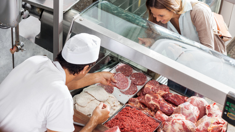 Butcher helps customer with meat