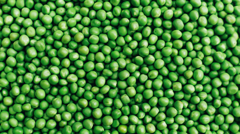 A closeup of lots of peas sitting together.