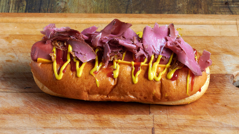 A pastrami dog is topped with pastrami, ketchup and mustard
