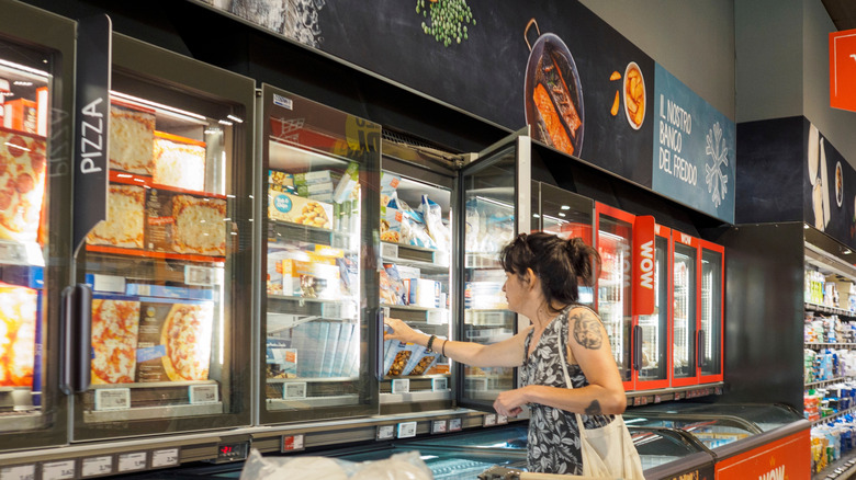 A shopper reaches into freezer at Aldi grocery store