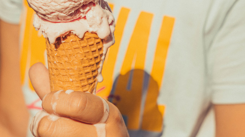 person holding dripping ice cream cone