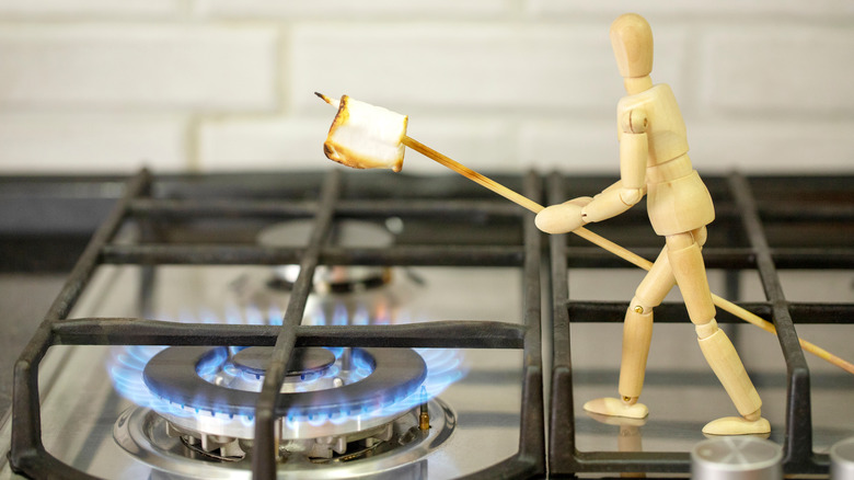 wooden figure roasts marshmallow on stove