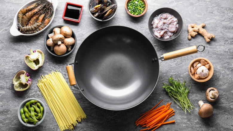A wok surrounded by a variety of different ingredients