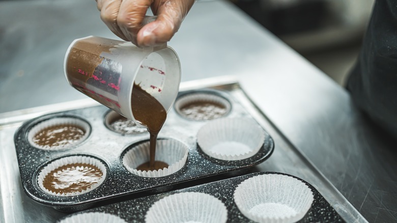 Hand filling cupcake liners with batter