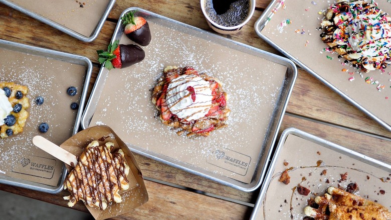 An array of waffles at Press Waffle Co., drizzled with chocolate and topped with fruit or sprinkles